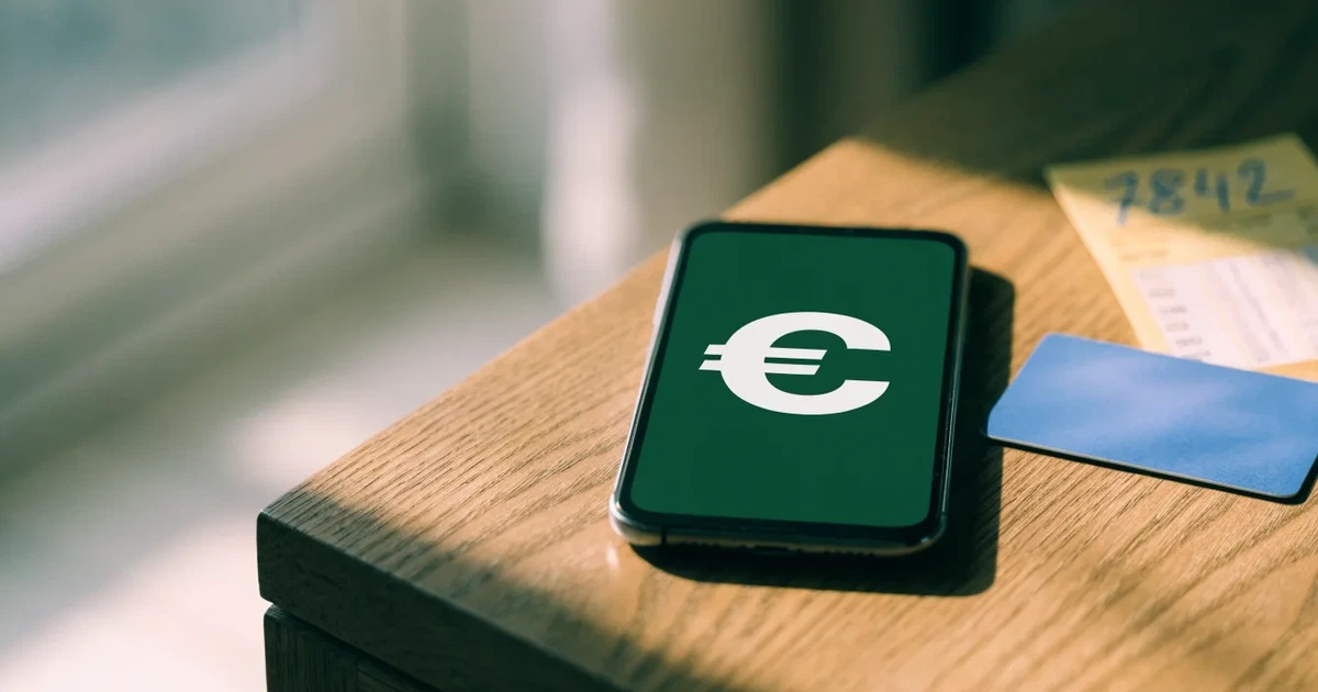 Uno smartphone e una carta di pagamento affiancati su un tavolo di legno, con alcune banconote da euro accanto